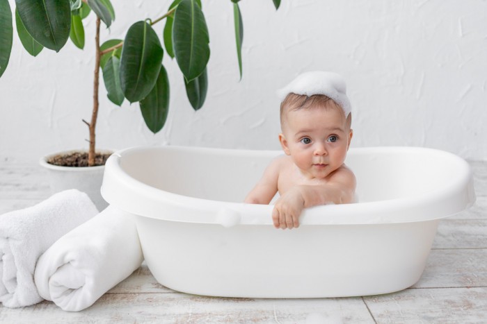 small child boy 8 months old bathes bath with foam soap bubbles 1