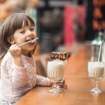 charming funny little girl drinks milkshake
