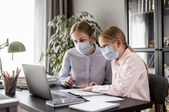 woman helping girl with homework while wearing medical mask 23 2148598019