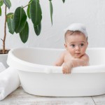 small child boy 8 months old bathes bath with foam soap bubbles 1