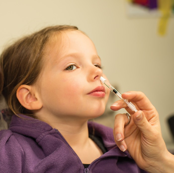 Photo of child being administered influenza vaccine live attenuated nasal 2