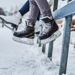 couple wearing ice skates sitting guardrail dating ice rink close up view skates