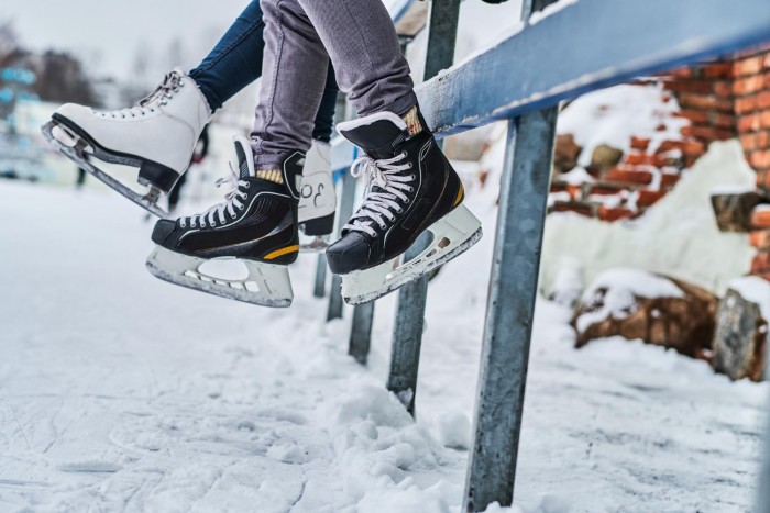 couple wearing ice skates sitting guardrail dating ice rink close up view skates