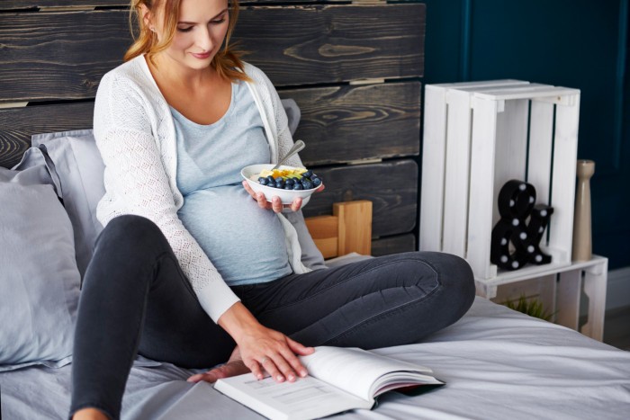 pregnant woman eating reading book
