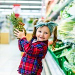 little kid standing with pineapple supermarket