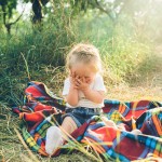 little girl covering her face sitting blanket floor